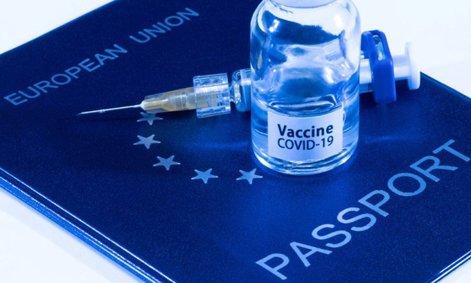 Ảnh minh họa hộ chiếu Liên minh châu Âu và lọ vaccine Covid-19. Ảnh: AFP.